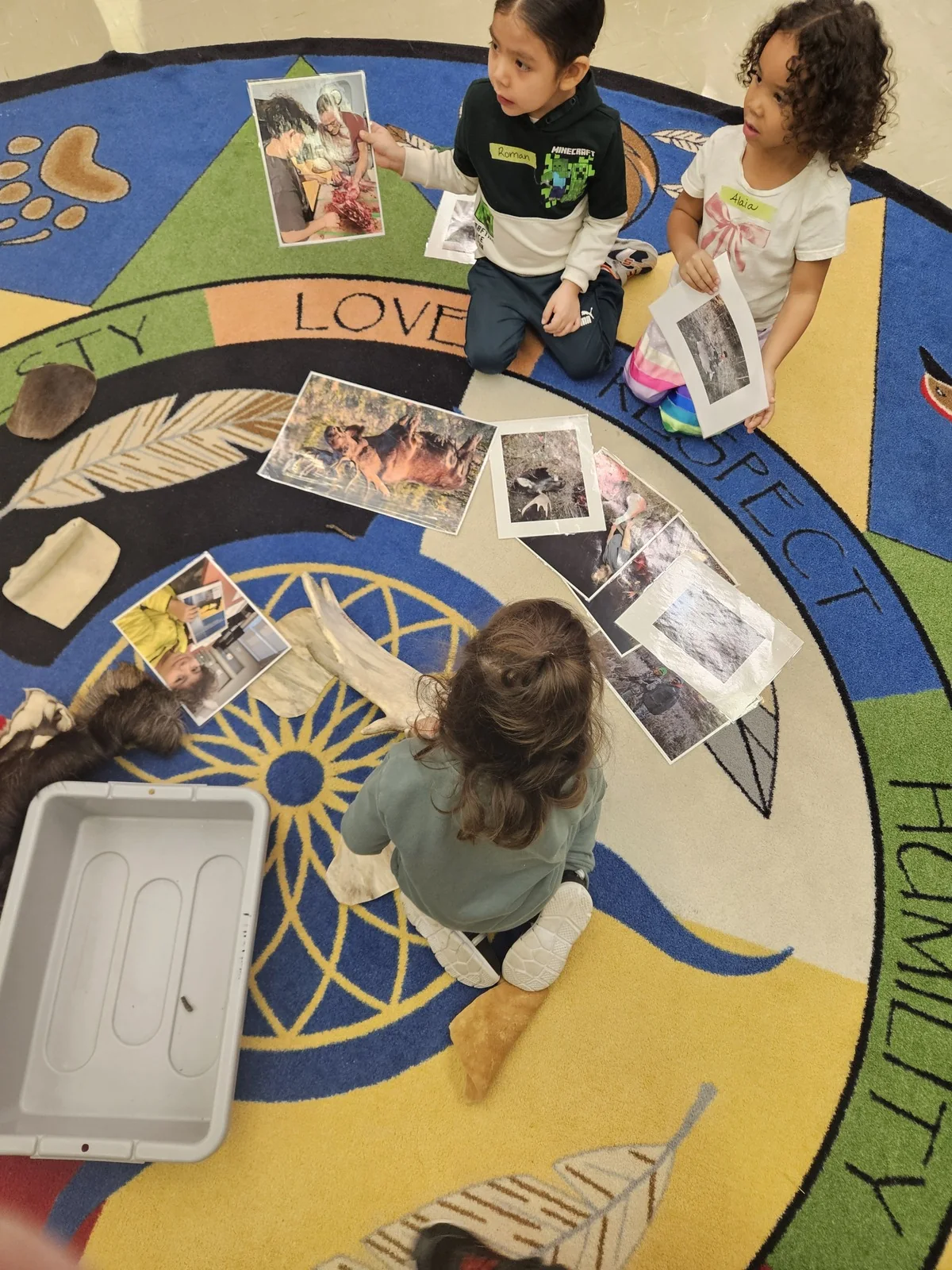 Two children arranging a row of photographs across the rug together.