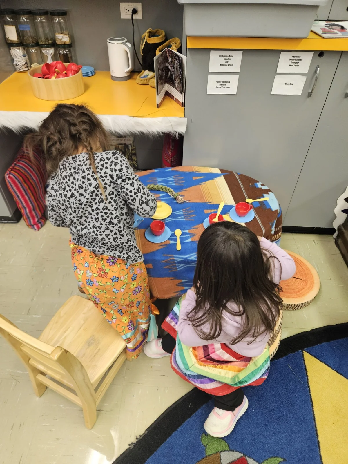 A child leaning over the painted table, working with a small brush.