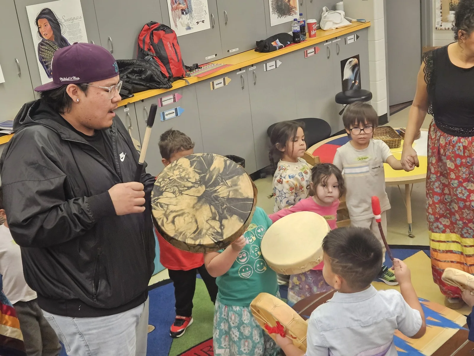 A child drumming in the foreground while the circle plays behind.