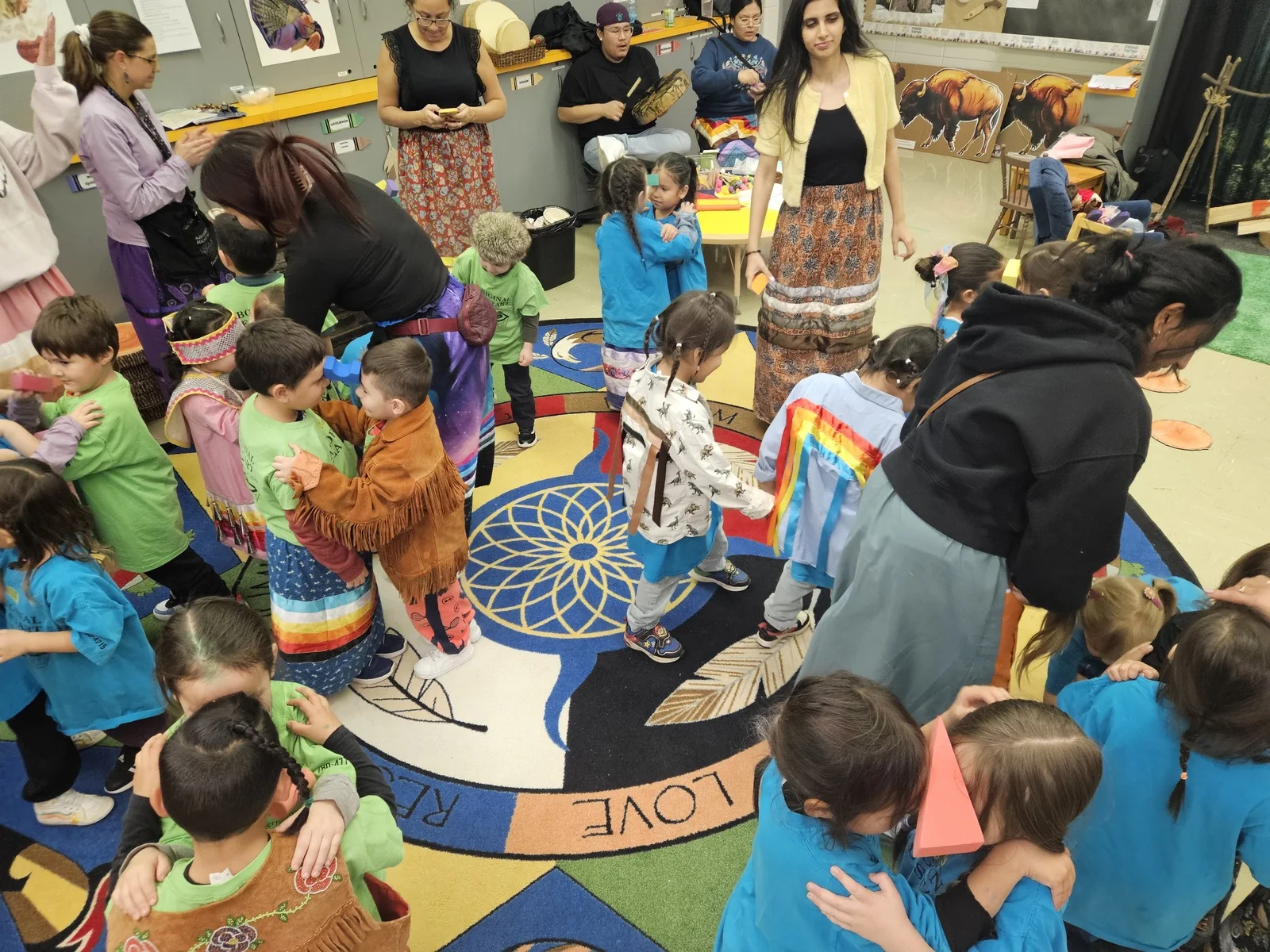 A crowded circle of children in coloured shirts gathered on the rug.
