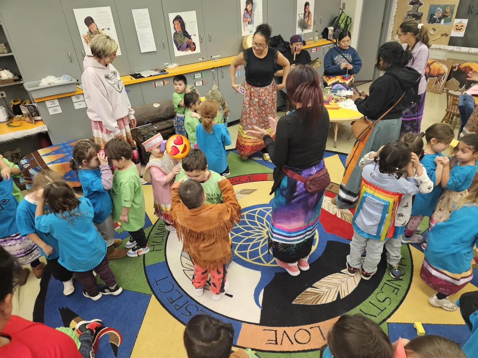 The group gathered together, a staff member in a ribbon skirt standing in the centre.